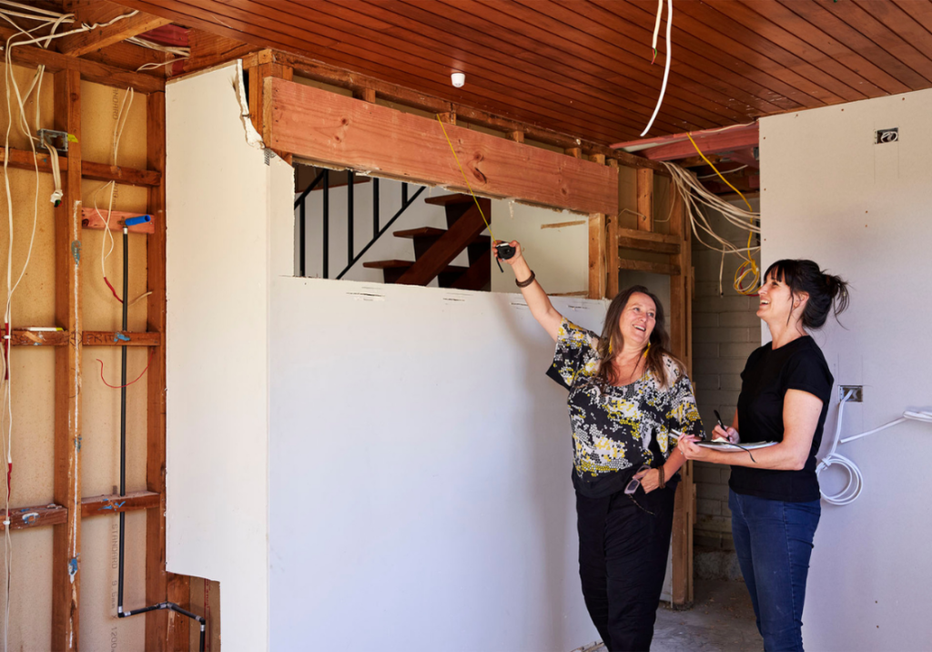 Designer and homeowners looking over architectural plans at a building site.